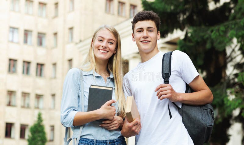 estudante segurando livros em frente a faculdade