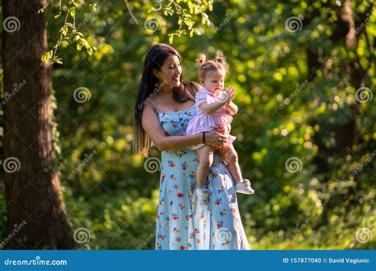 mae segurando bebe feliz no parque