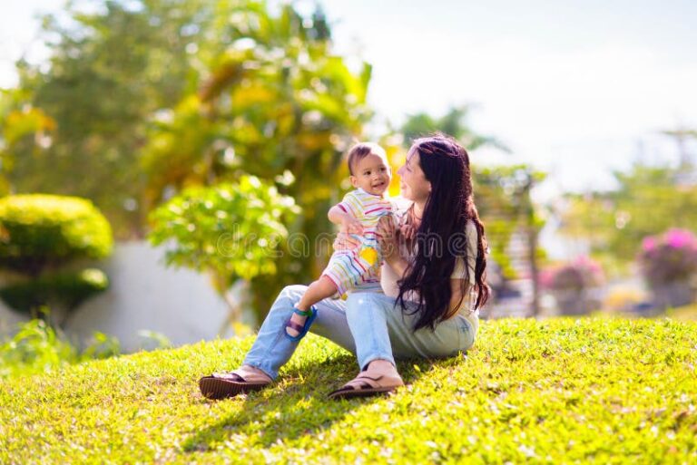 mae segurando o bebe em um parque