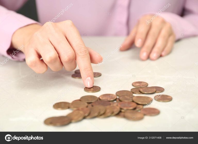 mao segurando moeda sobre uma mesa