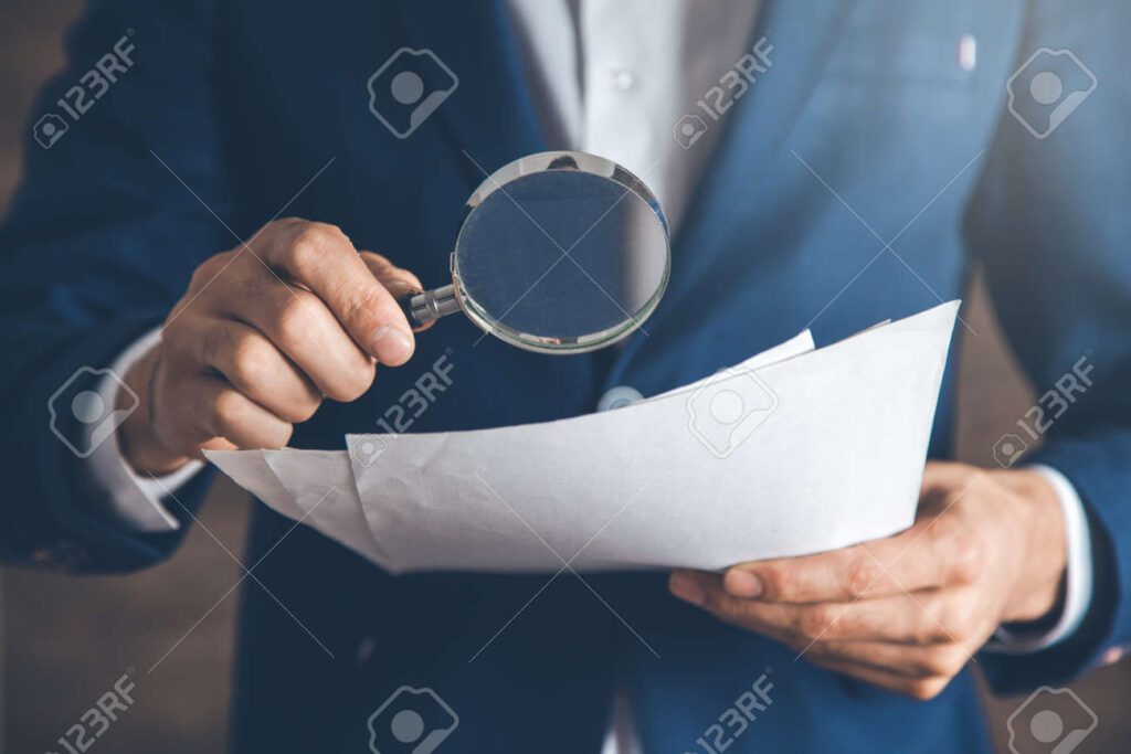 maos segurando uma lupa sobre um documento