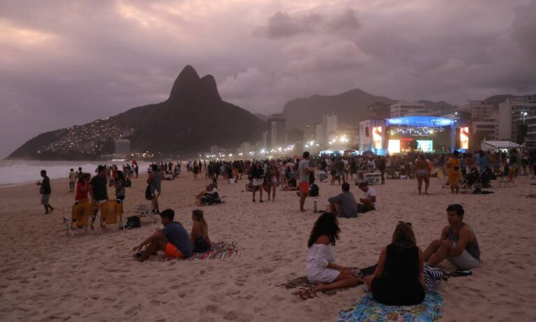 praia com quiosques e pessoas se divertindo