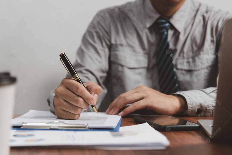 uma mao segurando uma caneta sobre documentos