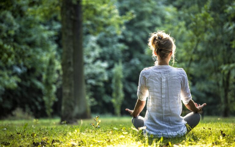 uma pessoa meditando em meio a natureza